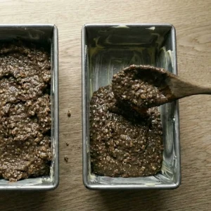Spoon the sticky saaristolaisleipä batter into greased loaf pans.