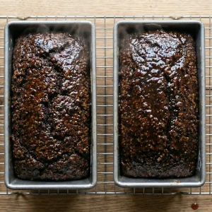 Freshly baked Finnish archipelago bread cooling in loaf pans on a rack.