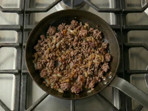 Ground beef and onions browning in a skillet for Finnish cabbage casserole