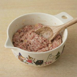 Mixed frikadeller fars (Danish meatball mixture) in a Martinex Tove Jansson Moomin mixing bowl with a wooden spoon.