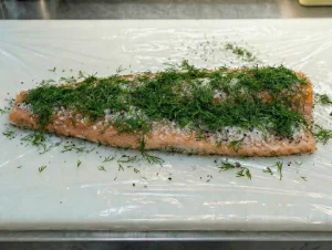 A seasoned salmon fillet topped with a generous layer of fresh chopped dill.