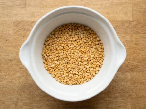 Dried yellow split peas in a white bowl on a wooden countertop