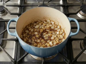 Diced onions sautéing in the Dutch oven, picking up browned bits for lapskaus stew.