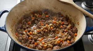 Ground beef, onions, and carrots simmering for Danish millionbøf just before thickening into gravy.