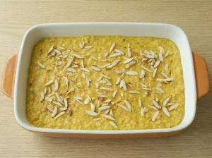 Unbaked saffron rice pudding mixture in a baking dish topped with sliced almonds.