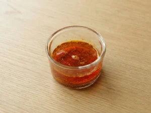 Small glass cup of saffron infusion, deep orange-red in color.