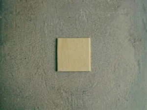 A single 4x4 inch square cut from rolled laminated Danish pastry dough, showing clean edges and thin layers