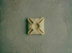 Danish pastry square with all four corners folded toward the center over remonce filling, forming the classic envelope shape