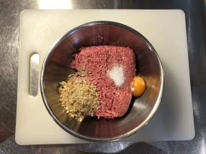 Ground beef in a bowl with an egg, breadcrumbs, and salt for a Swedish Operasmörgås.