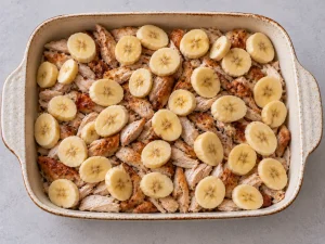 Banana slices arranged over chicken for Swedish Flying Jacob casserole