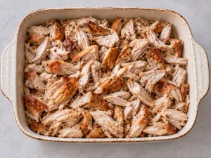 Pulled rotisserie chicken arranged in a baking dish for Flying Jacob